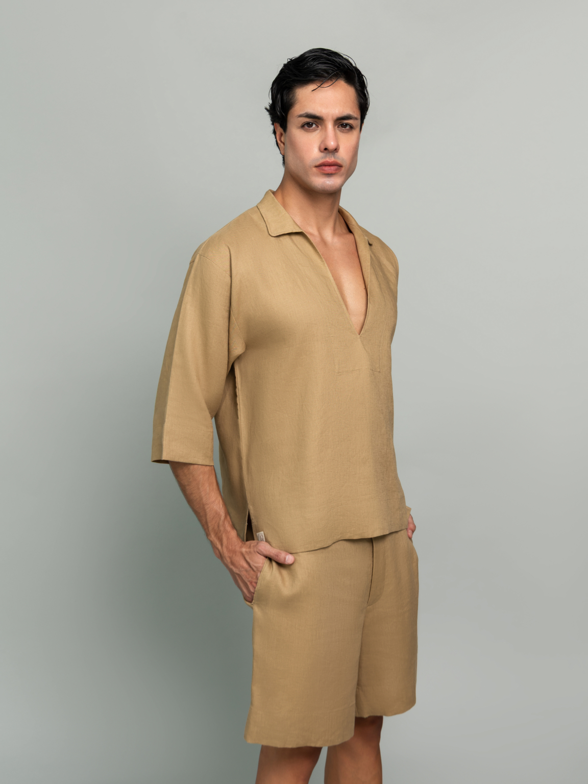 20Two Elemental GRAIN TOP and ROOT TROUSER in Sand Dune tan linen, lifestyle side profile beside white chair