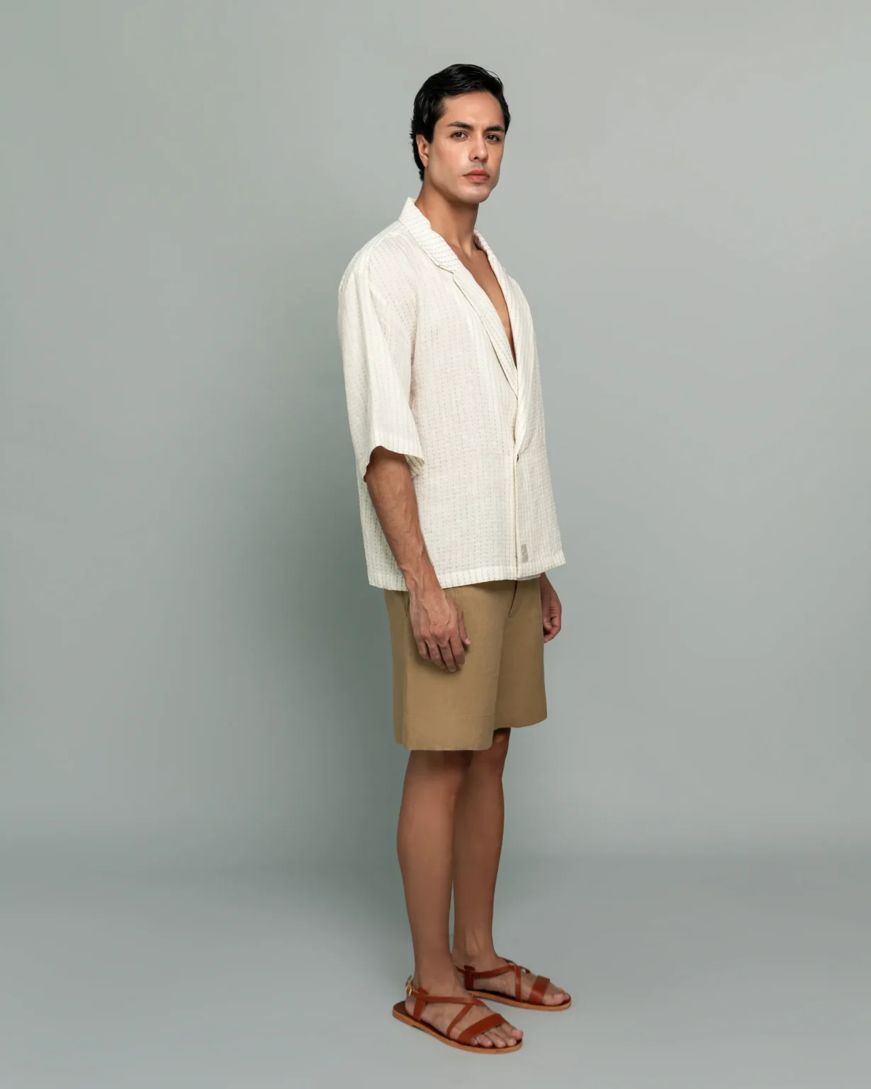 Side view of a man wearing 20Two Elemental's GHAF ivory over-shirt and desert tan drift short