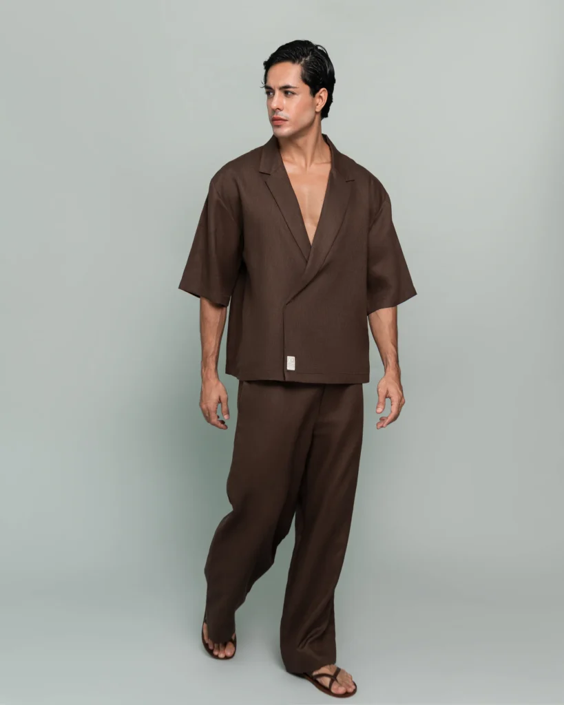 Close front detail of a man wearing 20Two Elemental's GHAF over-shirt and rooted trouser in brown, wrap-front shawl collar jacket