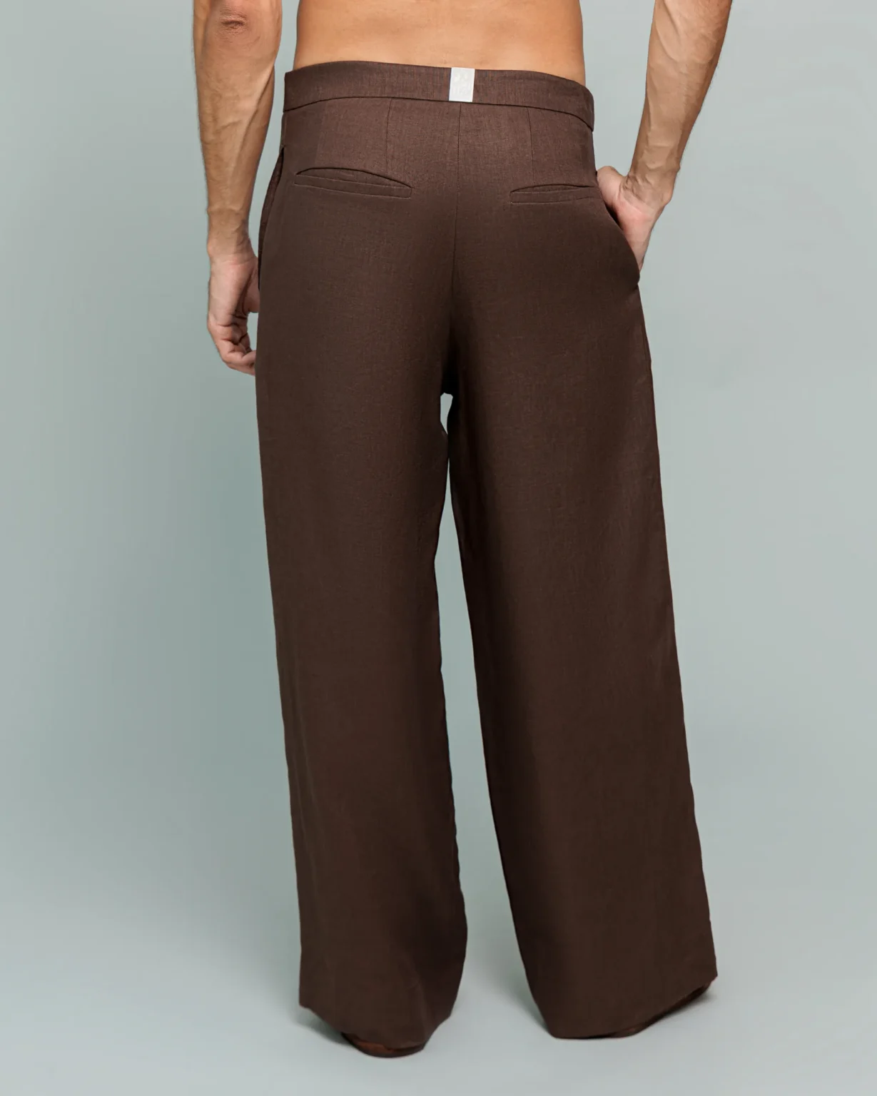 Back view of a man wearing 20Two Elemental's GHAF rooted trouser in brown, wide-leg silhouette, hands in back pockets