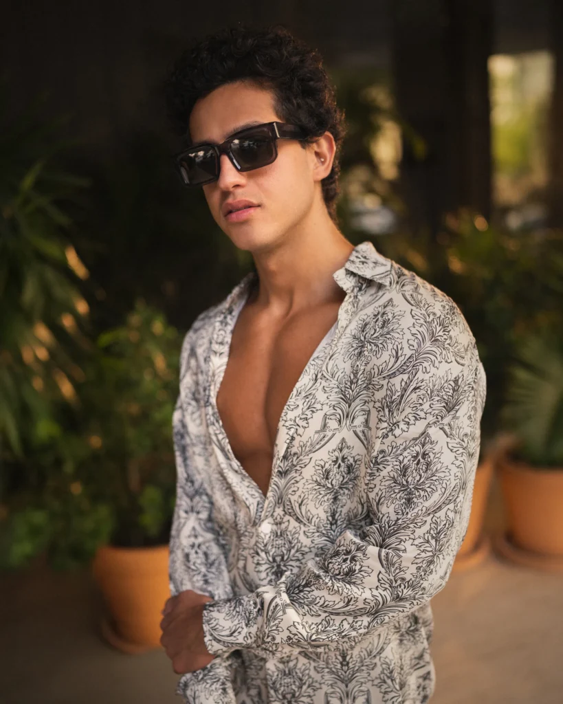 Man wearing a modern long-sleeve lotus plant fiber shirt from 20Two Elemental with a black-and-white botanical pattern, styled partially unbuttoned with bold dark rectangular sunglasses
